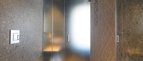 Un baño moderno con cabina de ducha de vidrio, lavamanos y retrete.