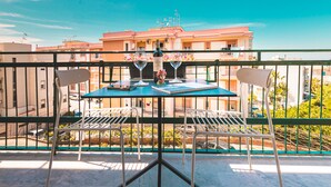 A balcony with a table and chairs, a bottle of wine, and a menu. - Nooria Sicilian Charme Rooms (Cefalù)