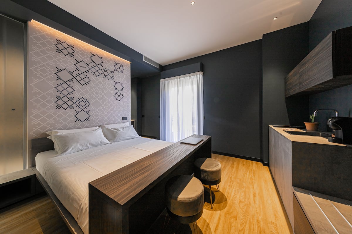 Ein modernes Schlafzimmer mit einem großen Bett, einem Holztisch und einer integrierten Küchenzeile.