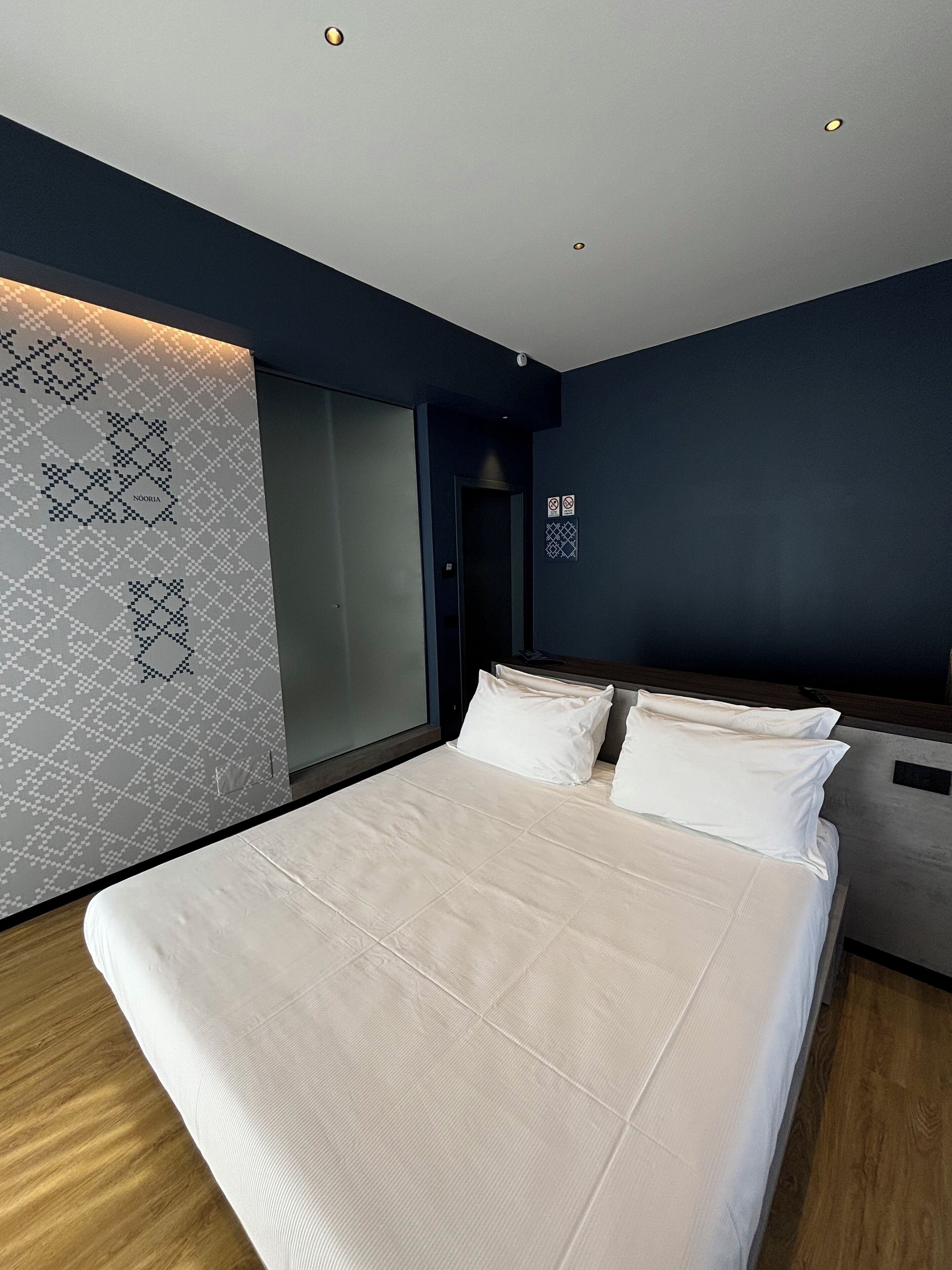 Ein modernes Schlafzimmer mit einem großen Bett, dunklen Wänden und einem gemusterten Wanddesign.