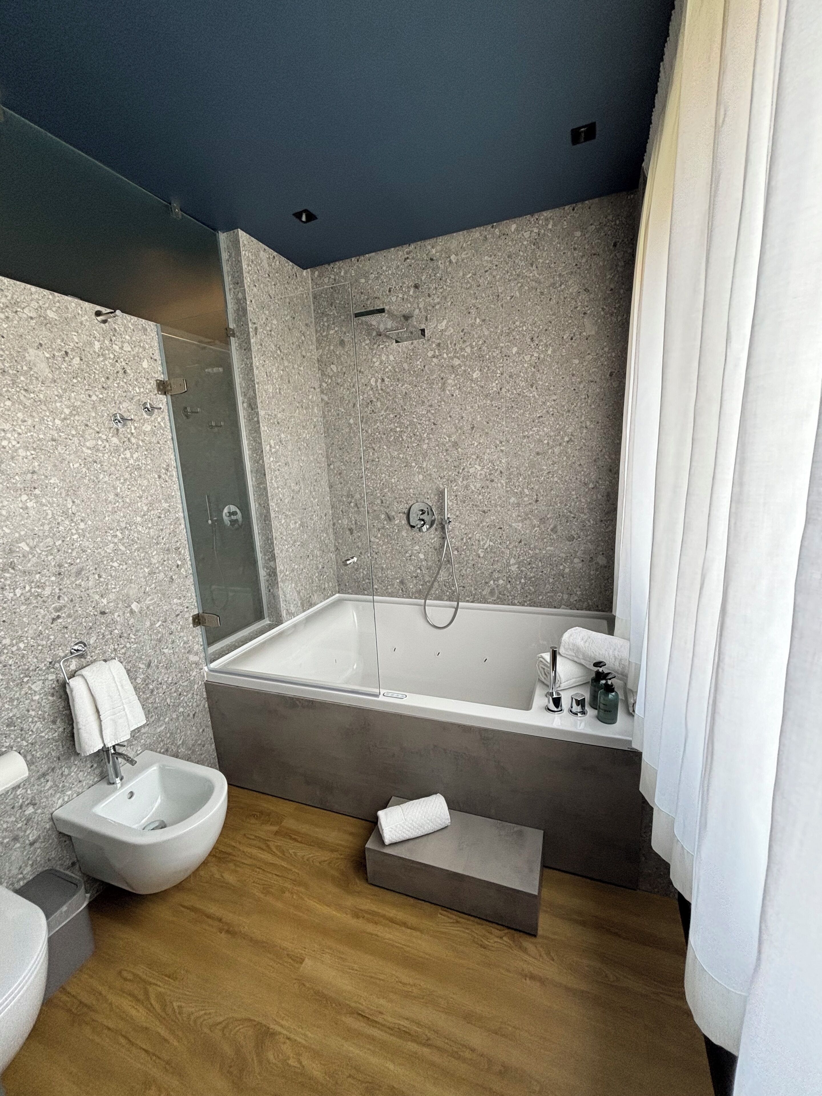 Een moderne badkamer met een vrijstaand bad, een toiletbril en een wastafel met spiegel.