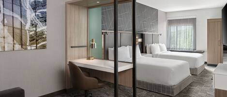A hotel room with two beds, a desk, a chair, a TV, and a large window.