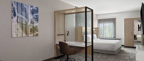Una habitación de hotel con cama, escritorio, silla y un espejo grande.