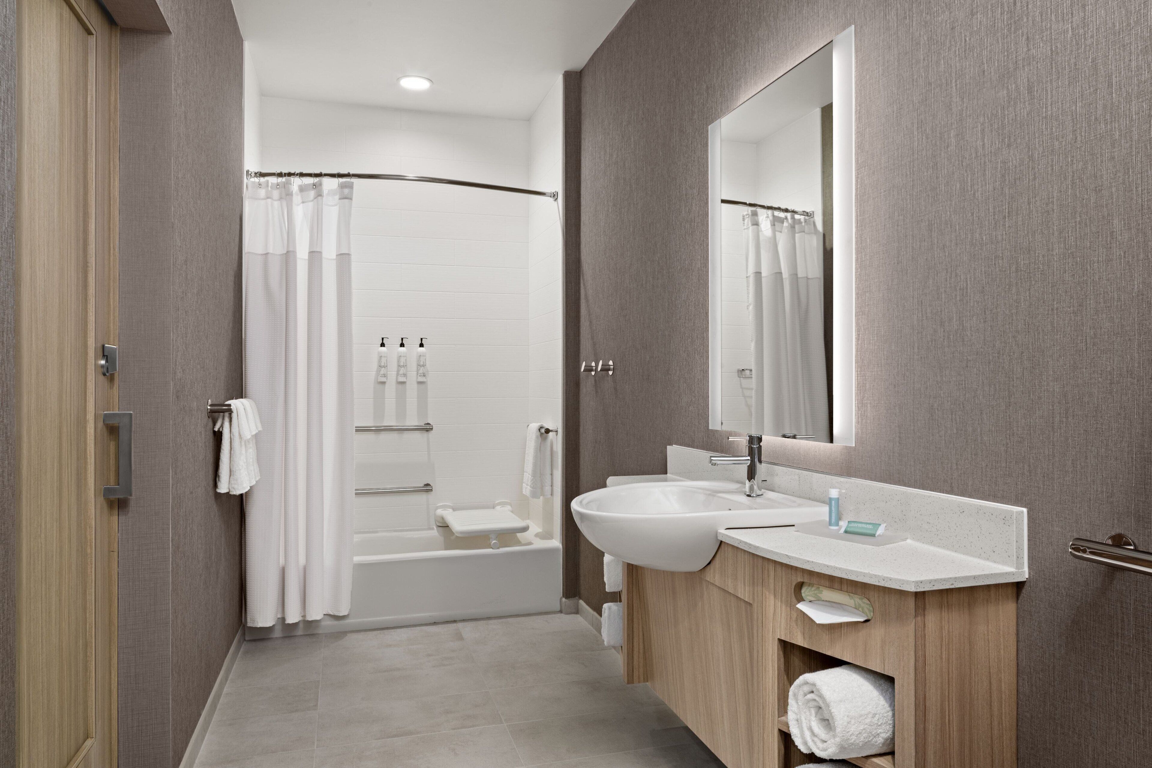 Un baño moderno con ducha, lavamanos y espejo.