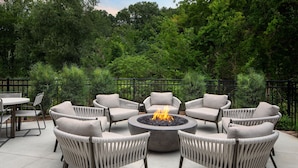 A circular outdoor seating area with a fire pit surrounded by wicker chairs. - Springhill Suites By Marriott Kalamazoo Portage (Portage)