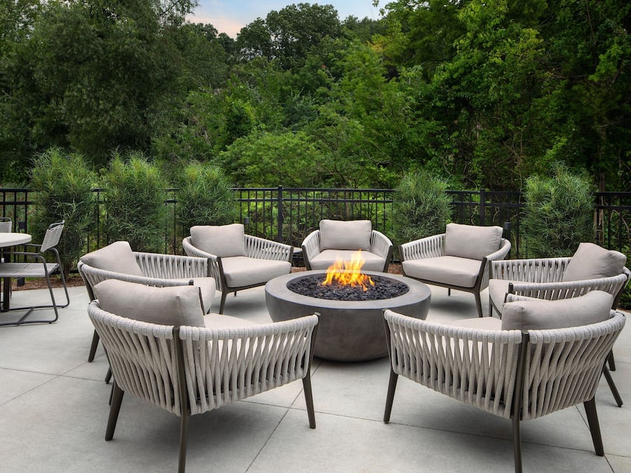 A circular outdoor seating area with a fire pit surrounded by wicker chairs.