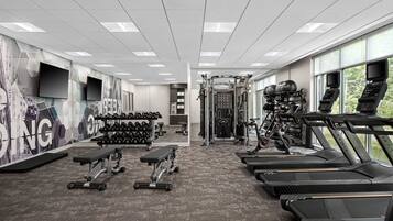 A gym with treadmills, dumbbells, and weight machines.