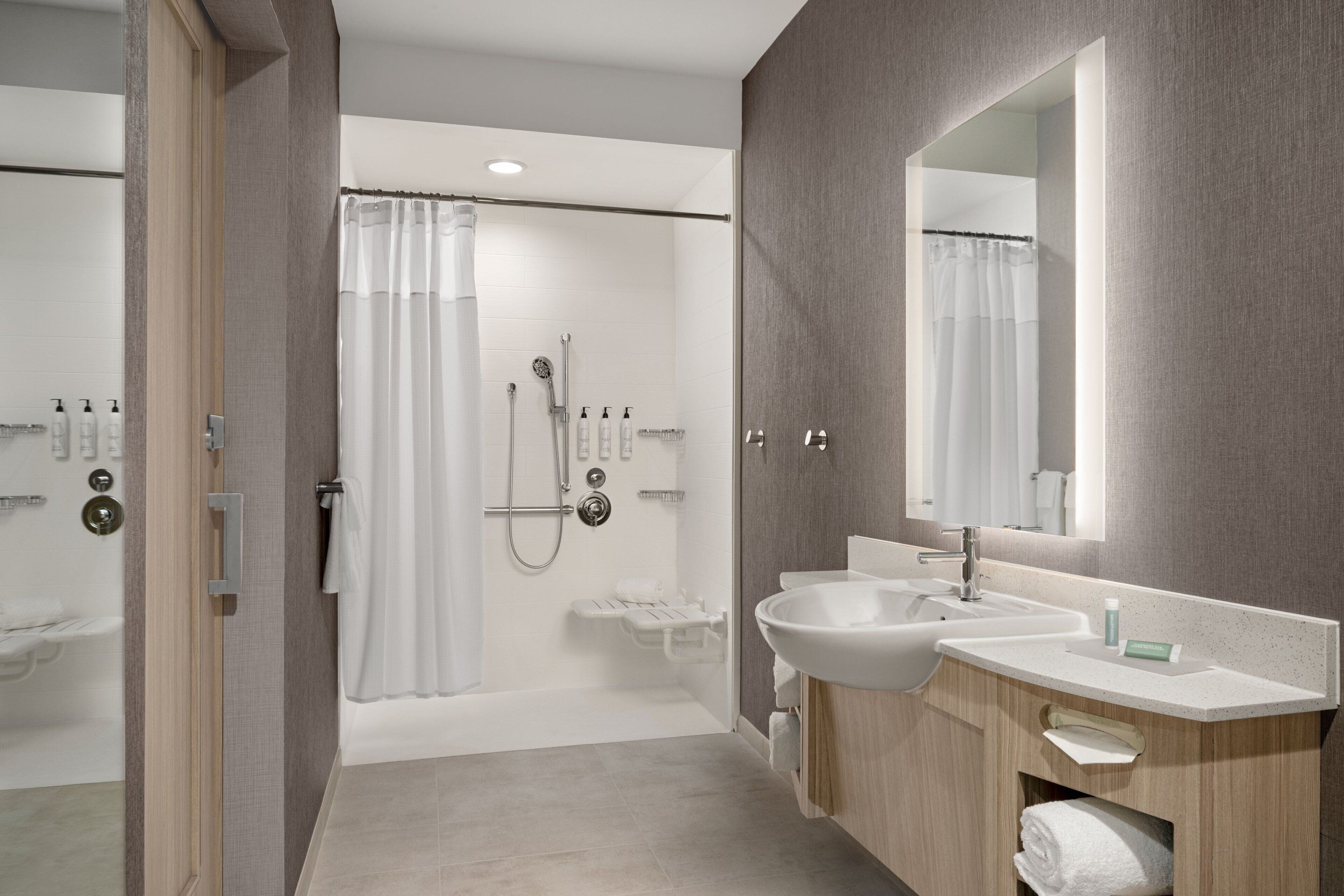 Un baño moderno con ducha a ras de suelo, lavamanos doble y un espejo grande.