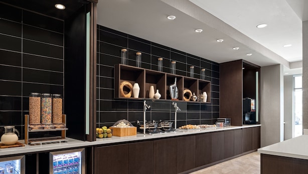 A modern kitchen with a built-in coffee station, refrigerated display, and a variety of food items. - Springhill Suites By Marriott Kalamazoo Portage (Portage)
