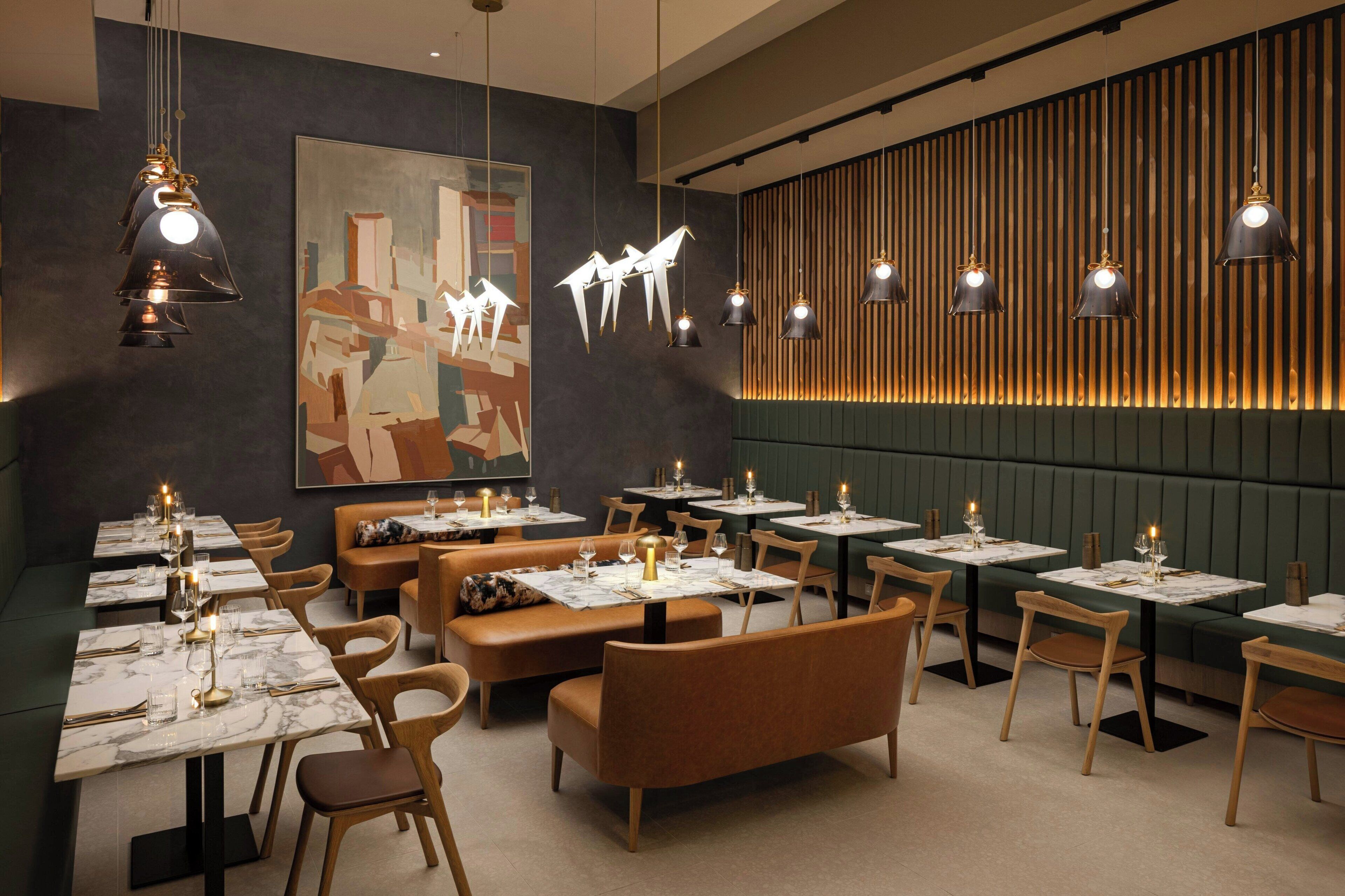 A modern restaurant interior with booths, tables, and hanging pendant lights.