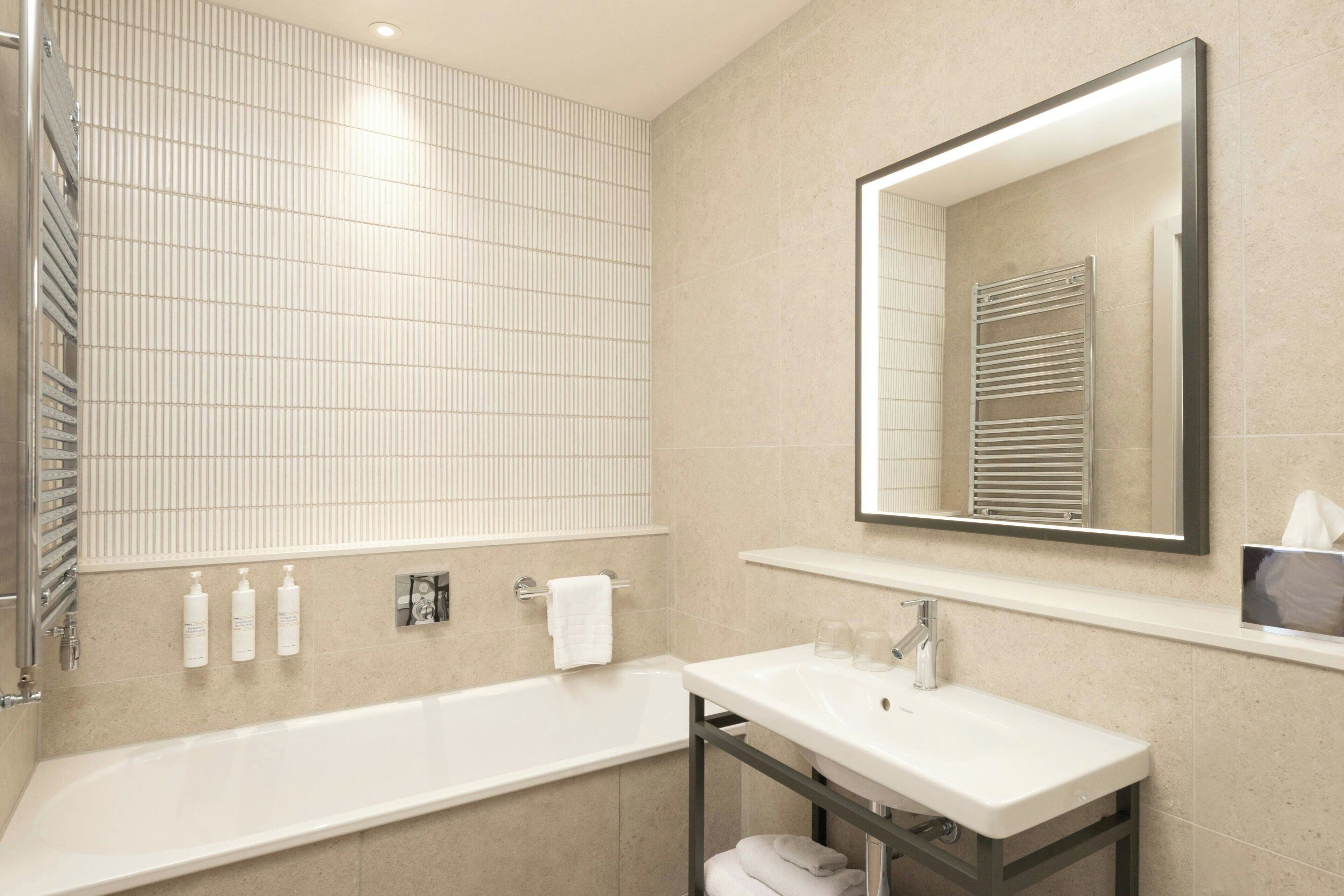 A modern bathroom with a bathtub, a sink, and a mirror.