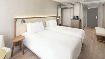 Una habitación de hotel moderna con una cama grande, una mesita de noche, una silla, un armario y una pequeña cocina.