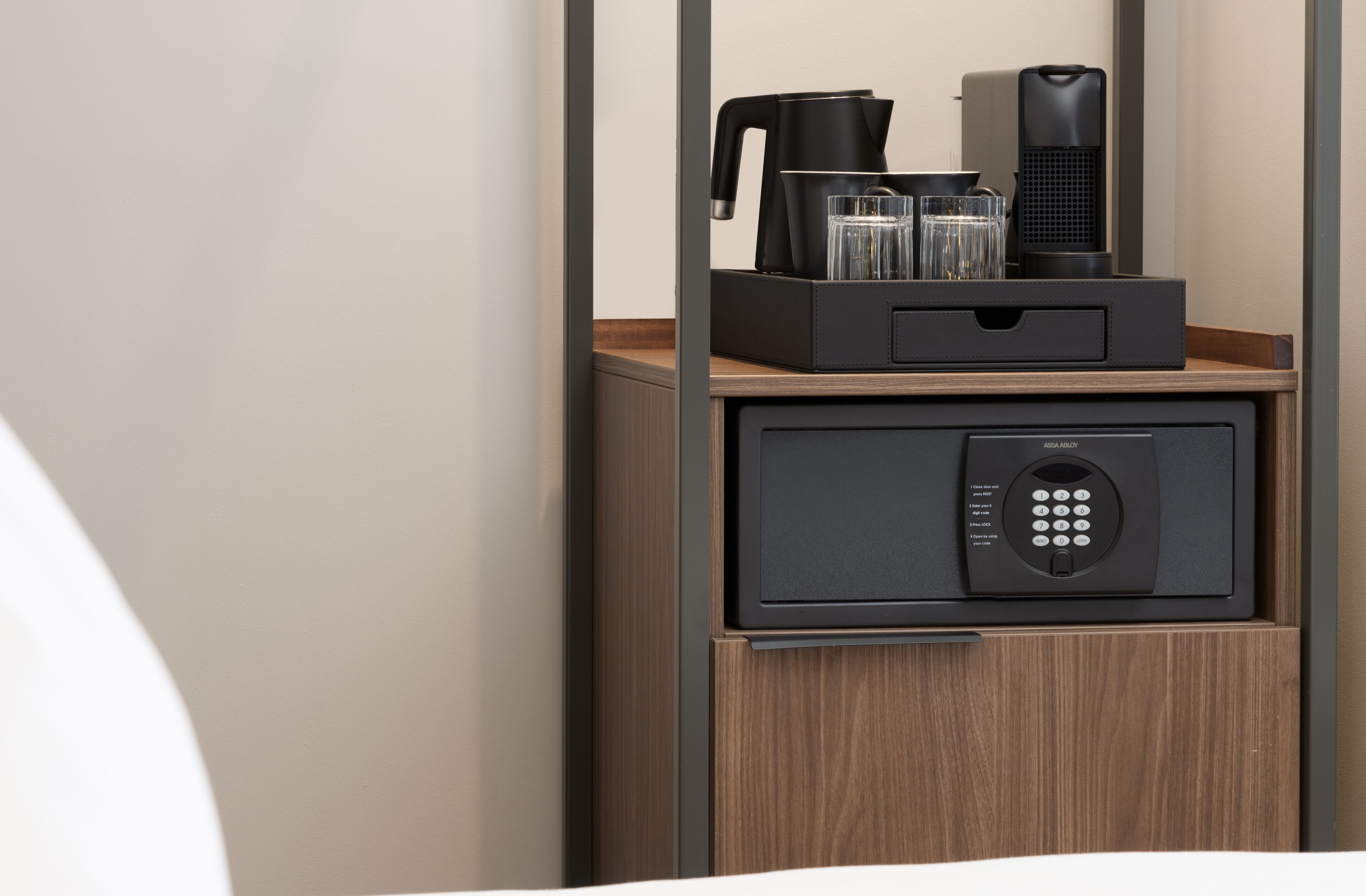 A minibar with a coffee maker, two glasses, and a speaker.