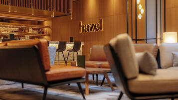 Un interior moderno con una zona de bar, asientos y un letrero con la palabra 'hazel'.