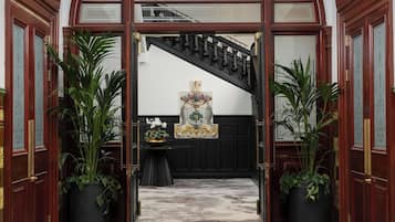 An entrance to a grand hall with a black carpet and a sign reading "The Collector's Hall."