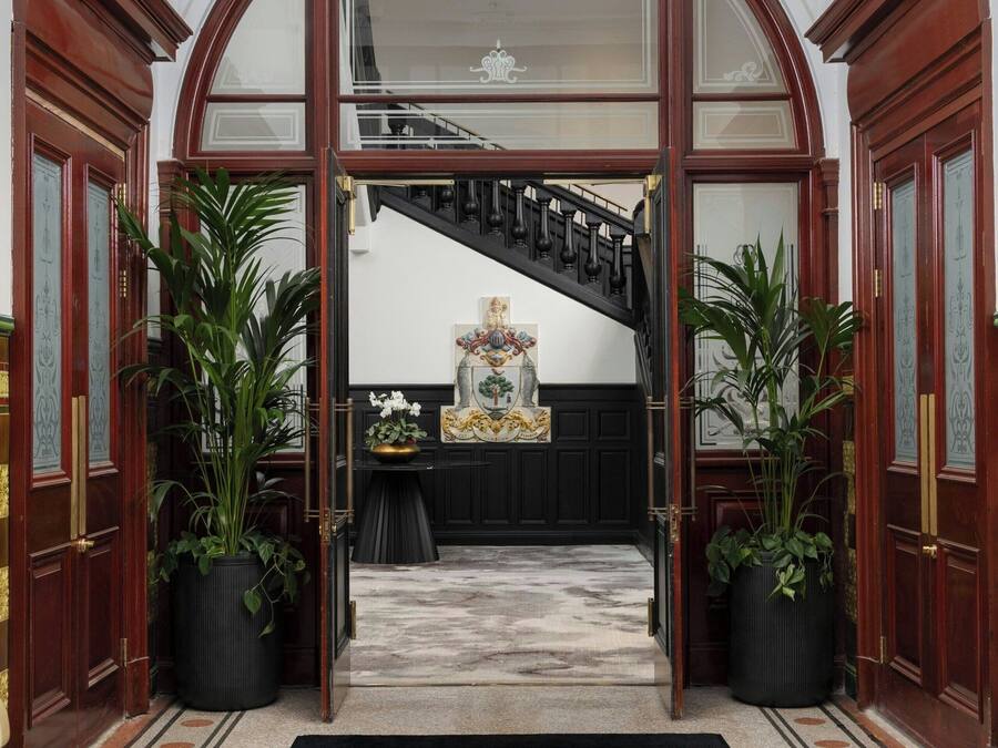 An entrance to a grand hall with a black carpet and a sign reading "The Collector's Hall."