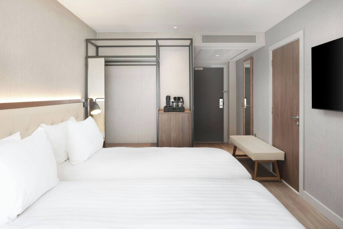 Ein Hotelzimmer mit einem großen Bett, einer Bank, einer Kaffeemaschine und einem Fernseher an der Wand.