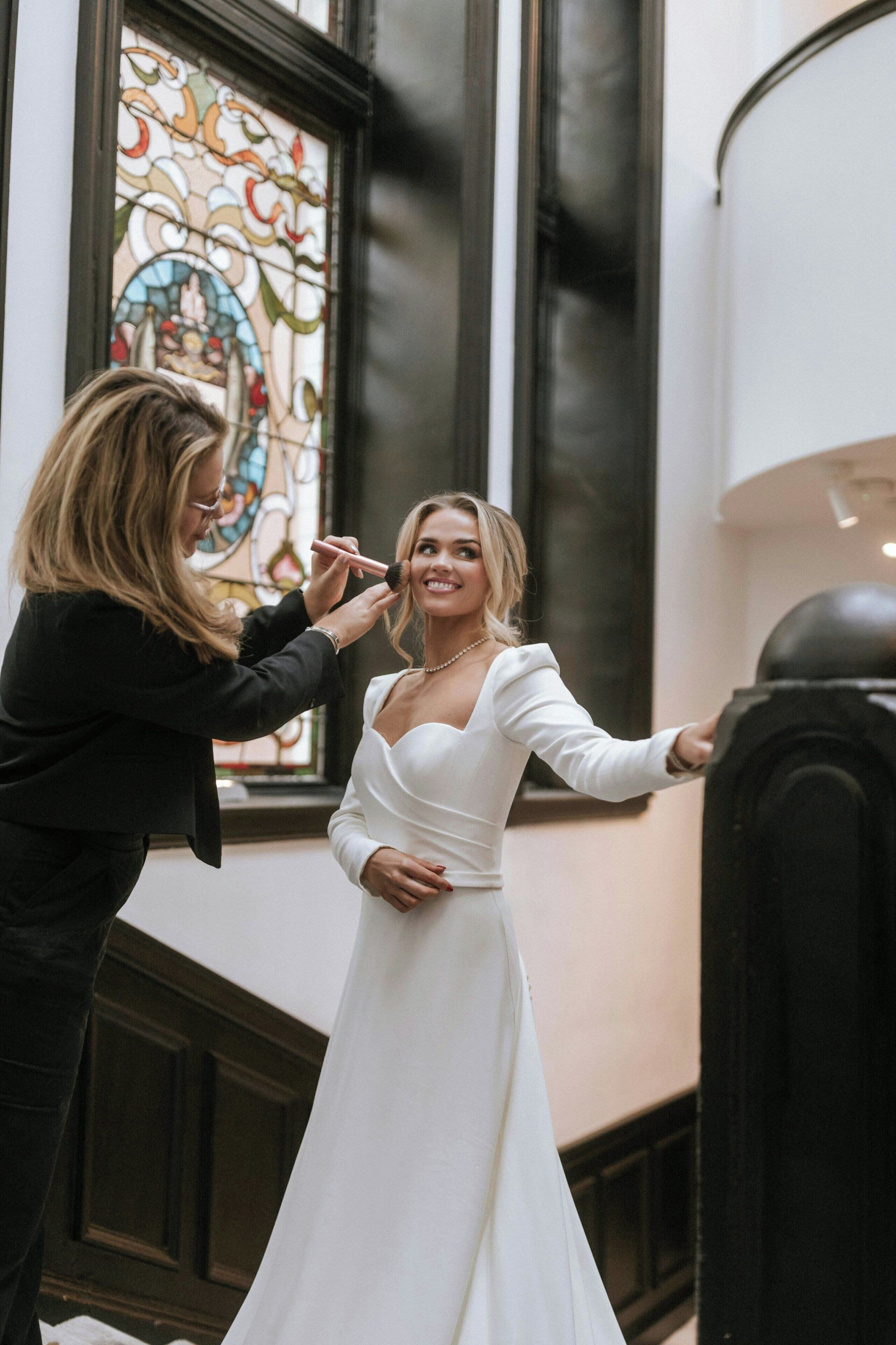 Una mujer con vestido blanco recibiendo ayuda de otra persona.