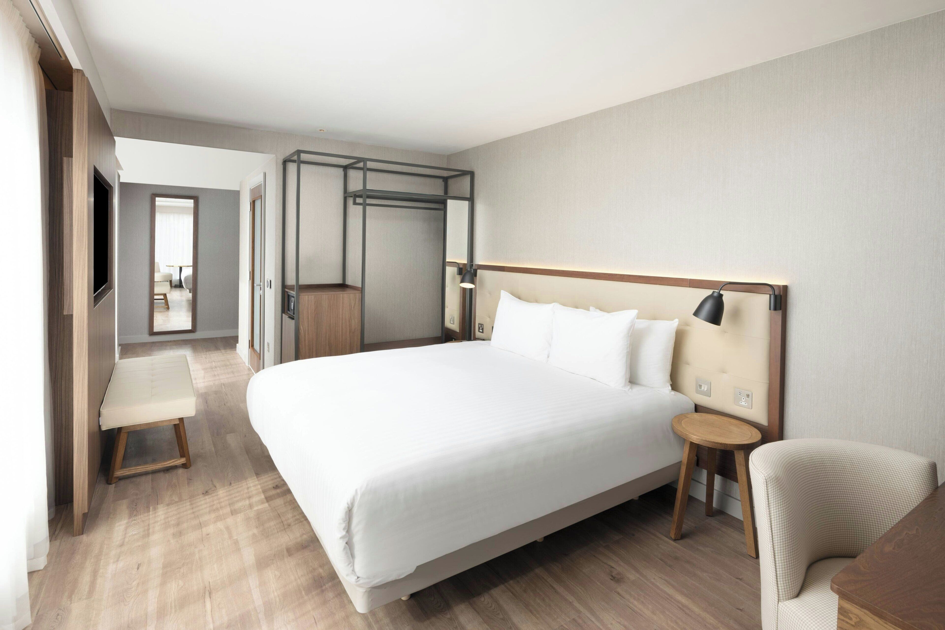 Une chambre d’hôtel moderne avec un grand lit, une table de chevet, une chaise et un téléviseur.