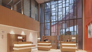Un hall d’accueil moderne avec deux comptoirs de réception, de grandes fenêtres et un plafond haut.