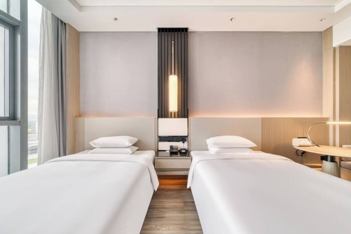 Habitación de hotel con dos camas, una mesita de noche, un espejo y una ventana.