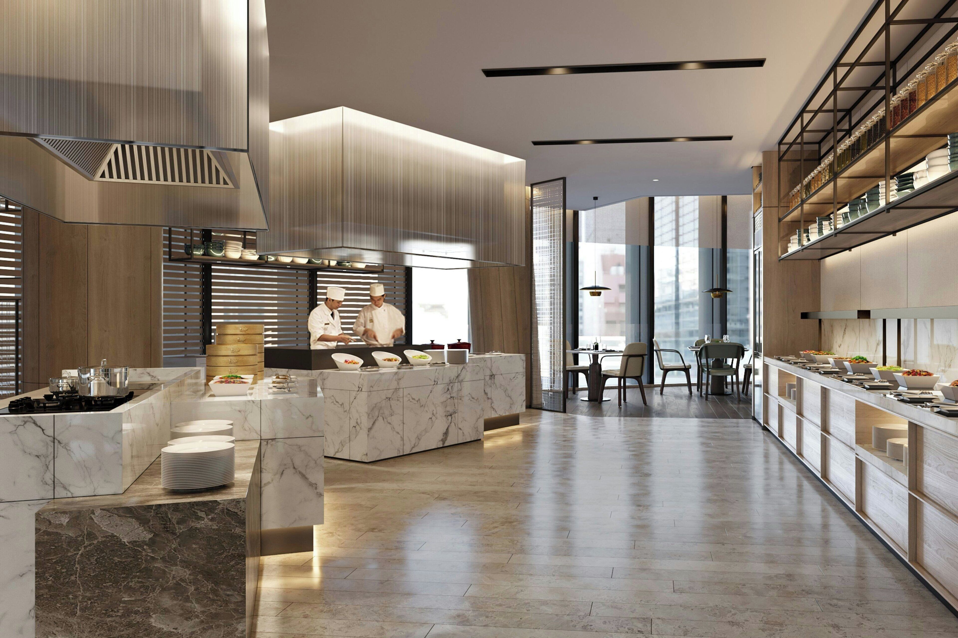 A modern kitchen with marble countertops, a central island, and a dining area with a high ceiling and large windows.