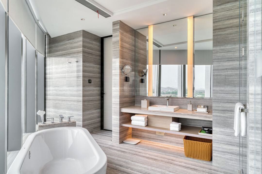A modern bathroom with a freestanding bathtub, a vanity with a mirror, and a large window offering a view.