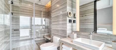 Un baño moderno con cabina de ducha de vidrio, inodoro blanco, lavamanos grande y espejo.