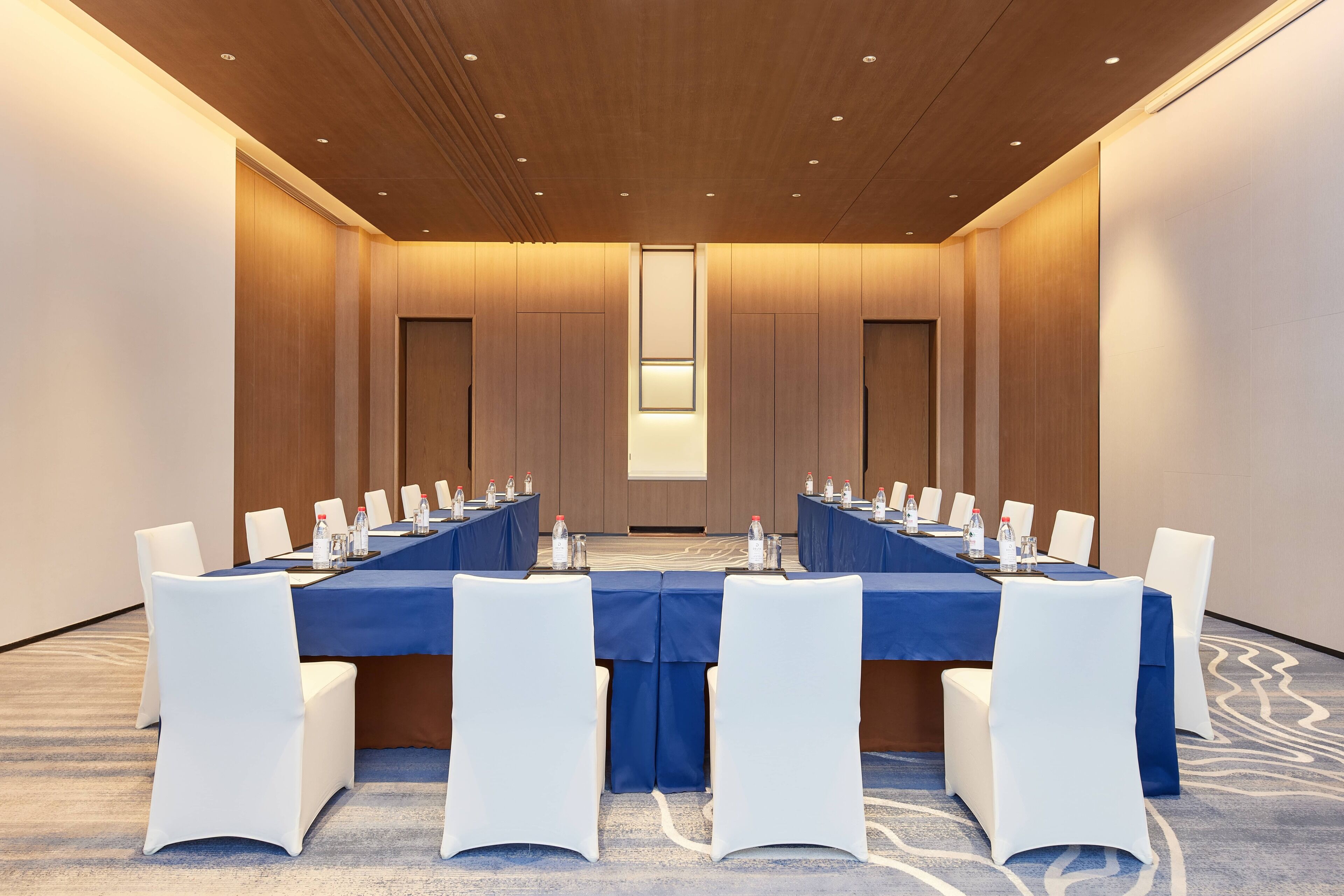 A conference room with a long table, white chairs, and water bottles.