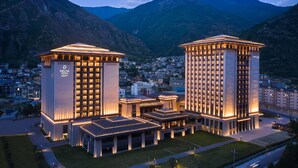 Un hôtel moderne, doté d’une entrée imposante et de plusieurs étages, situé dans un environnement montagneux.