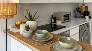 Une cuisine moderne dotée d’un plan de travail en bois, d’un four à micro-ondes, d’un lave-linge et de divers ustensiles de cuisine.