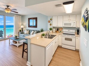 A modern kitchen with white cabinets, a central island, and a view to the outside.