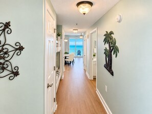 A hallway with a view to a balcony, a dining area, and a ceiling light fixture.