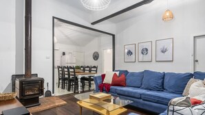 A modern living room with a blue sofa, a glass coffee table, and a wooden floor.