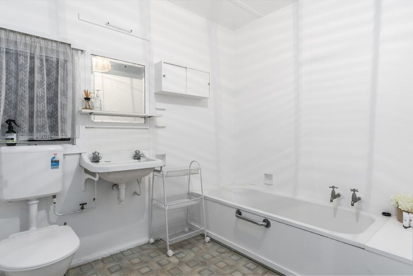 Une petite salle de bain blanche, équipée de toilettes, d’un lavabo et d’une douche.