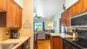 Una cocina con gabinetes de madera, lavavajillas, estufa y ventilador de techo.