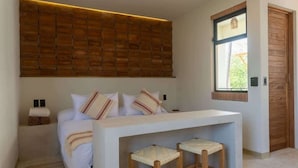 Ein modernes Schlafzimmer mit Bett, Nachttischen, einer Bank und einem Fenster.