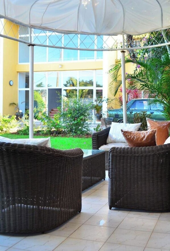 An outdoor seating area with wicker furniture and a covered section. - Room in Villa - The Elegant Villa Alexandre Near Ivato Airport.' (Antananarivo)