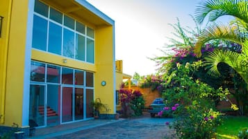 A yellow building with large windows and a paved entrance area.