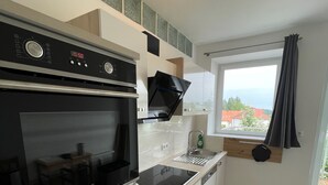 Una cocina moderna con horno integrado, lavavajillas y una ventana con cortinas.