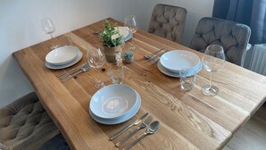 Una mesa de comedor lista con platos, cubiertos y vasos, rodeada de sillas tapizadas.
