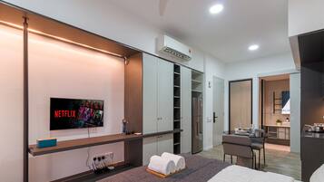 Une chambre d’hôtel moderne équipée d’une télévision à écran plat avec accès à Netflix, d’un minibar, d’un bureau avec une chaise, d’une kitchenette et d’un dressing.