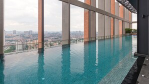 A rooftop infinity pool with a city view, large glass windows, and a modern architectural design.