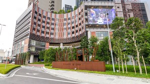 A modern building with a curved facade, a large digital billboard, and a sign that reads "SQUARE @ OKR".