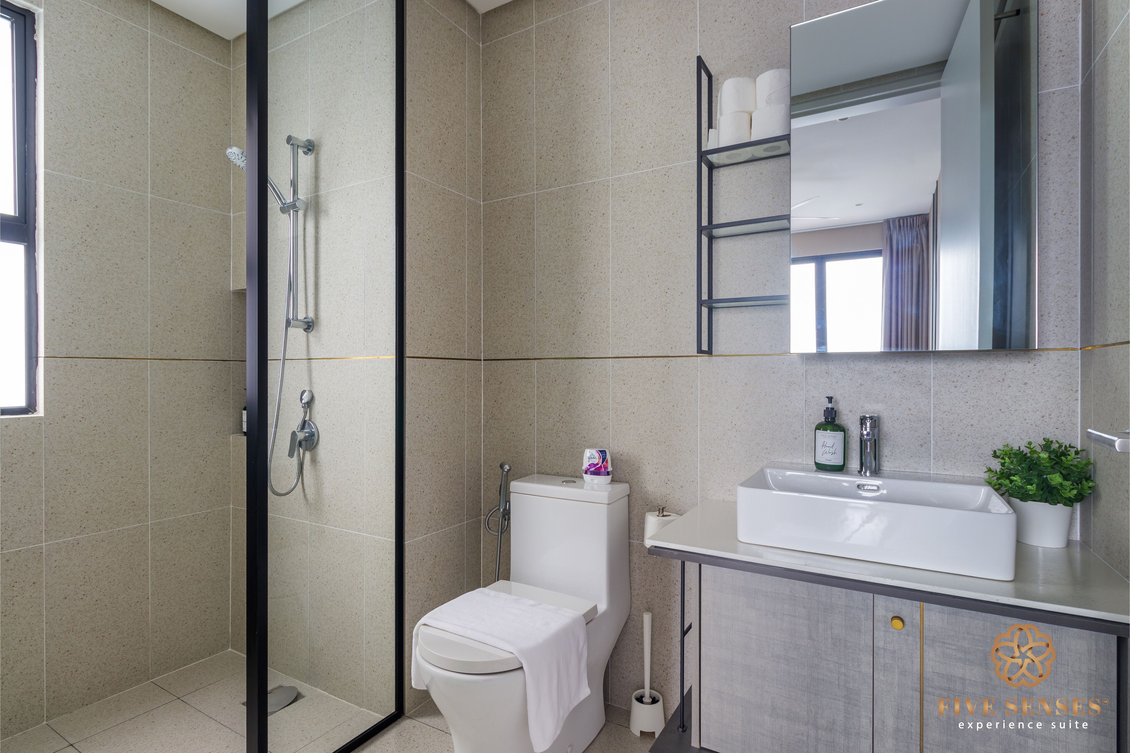 A modern bathroom with a shower, toilet, sink, and a mirror.