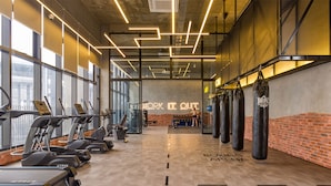A gym with treadmills, punching bags, and a neon sign that reads "WORK IT OUT".