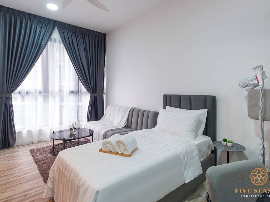 A hotel room with a bed, a chair, a small table, and a massage chair.