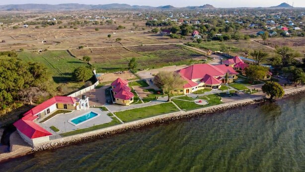 An aerial view of a coastal property with multiple buildings, a swimming pool, and a waterfront. - SANDMARK HOTEL SERENGETI  (Bariadi)