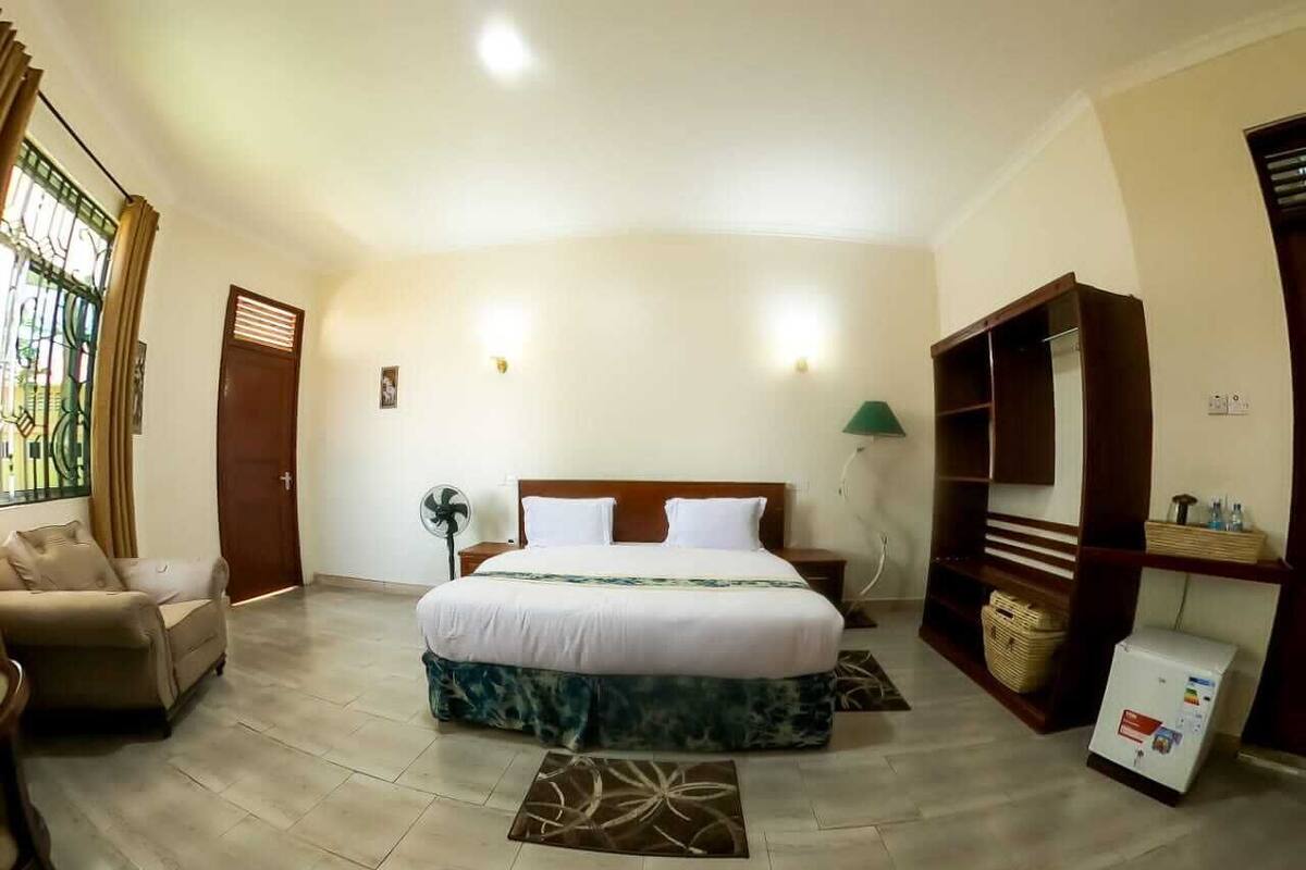 A bedroom with a bed, a sofa, a desk, and a refrigerator.