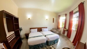 A hotel room with two beds, a wooden bench, a desk, and a chair. - SANDMARK HOTEL SERENGETI  (Bariadi)